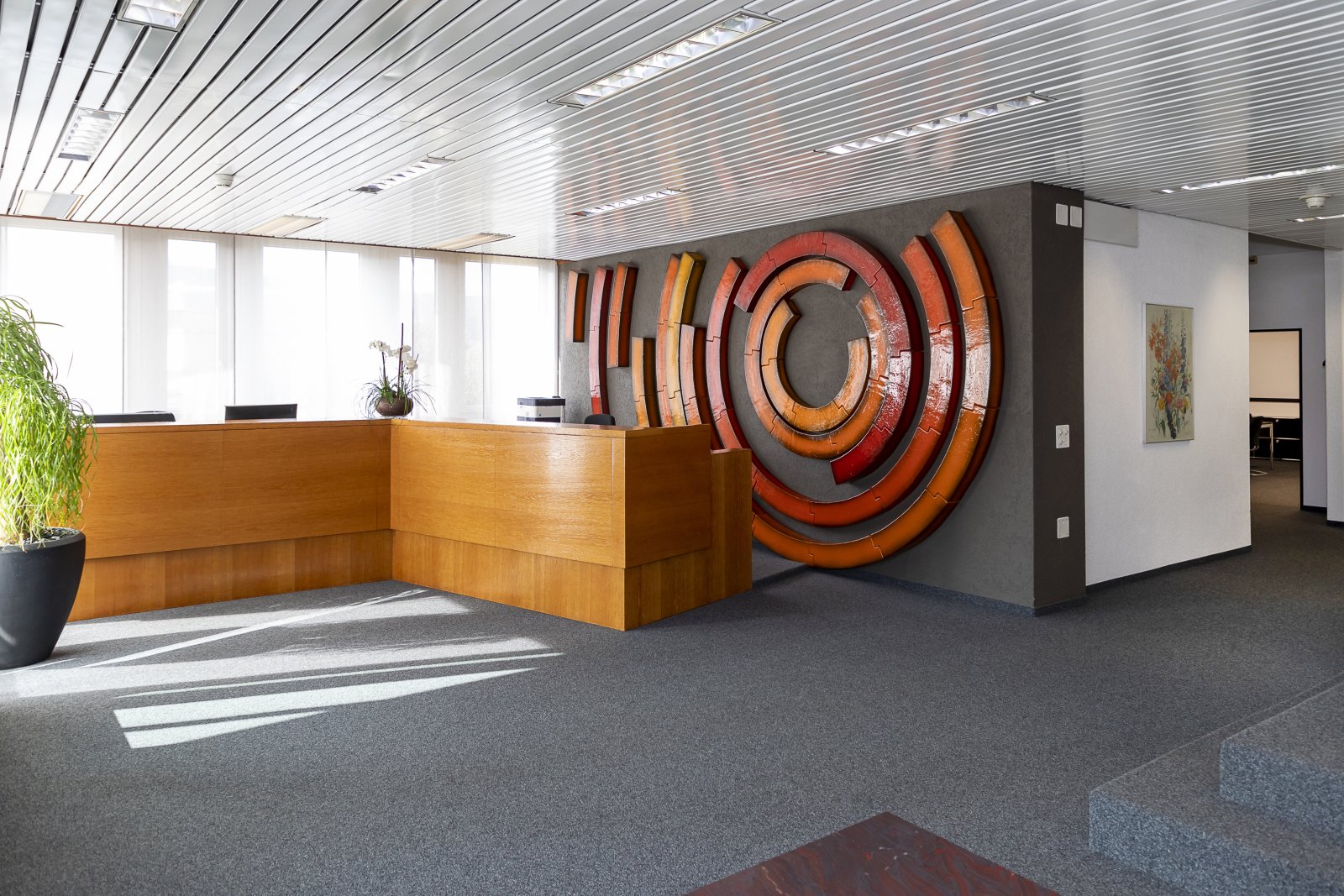 Repräsentative Empfangszone mit designorientierter Wandkunst und hochwertiger Holztheke