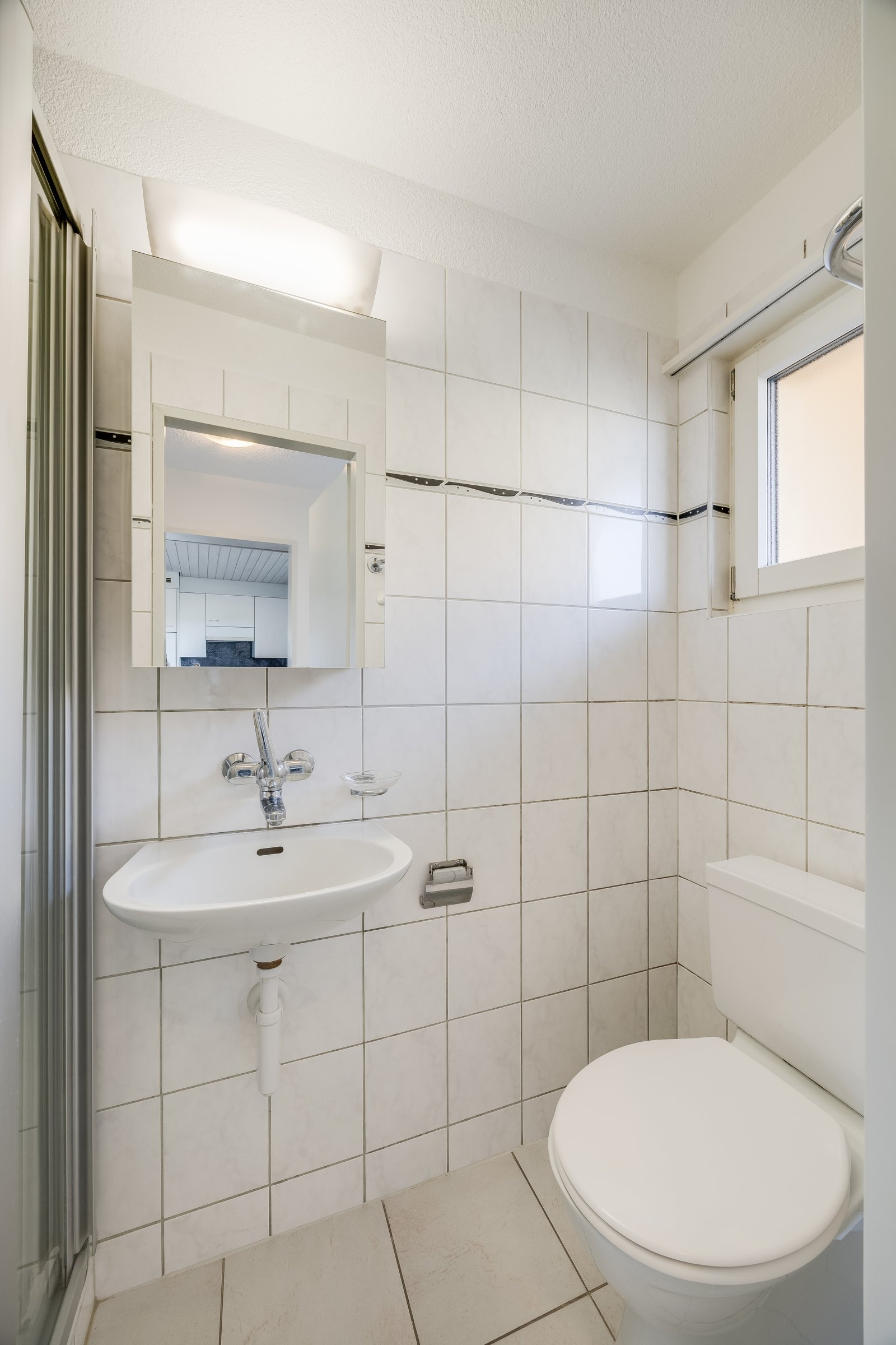 Praktisches Badezimmer mit Dusche, Waschtisch und Spiegelschrank