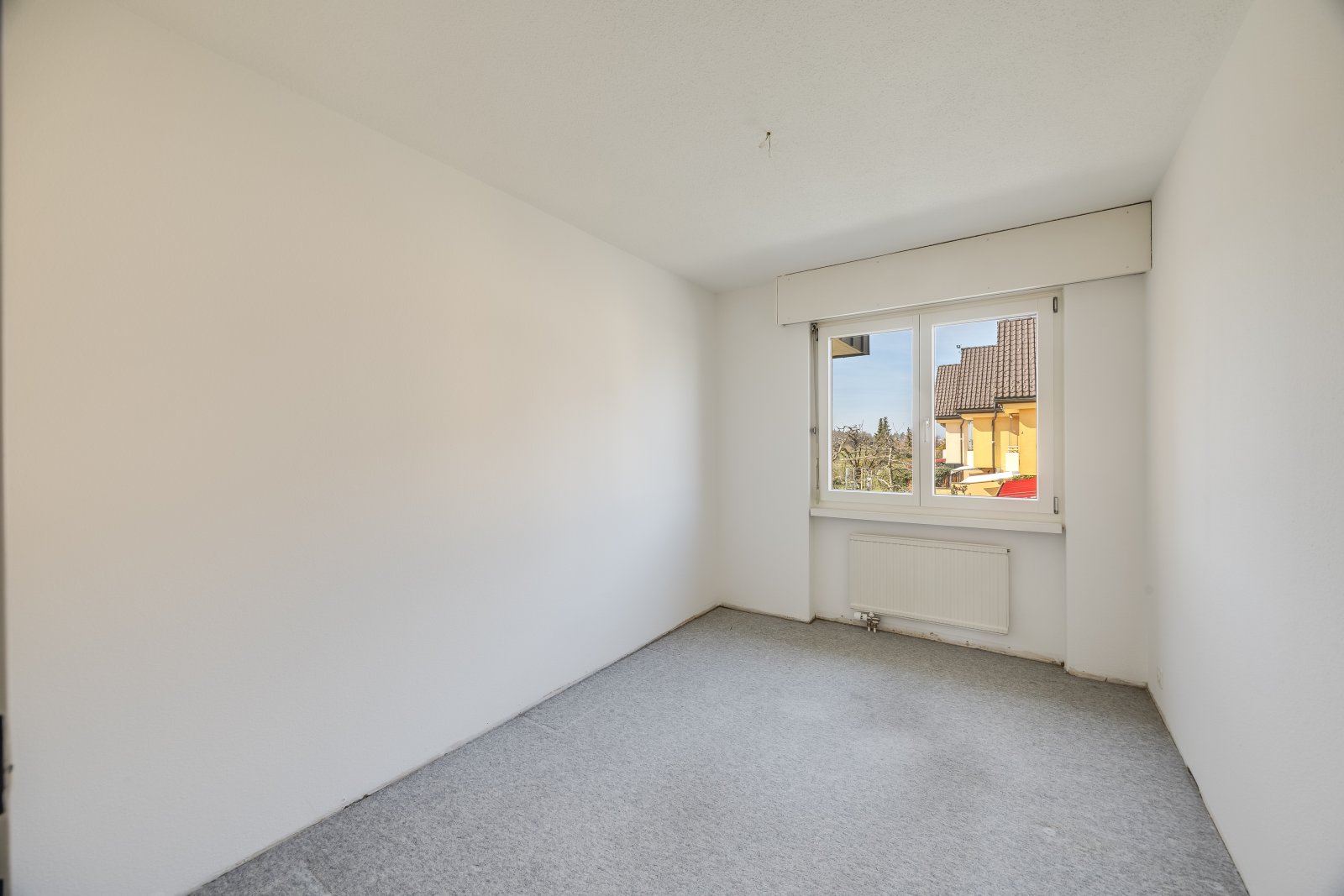 Helles Zimmer mit Fensterfront und Ausblick ins Grüne